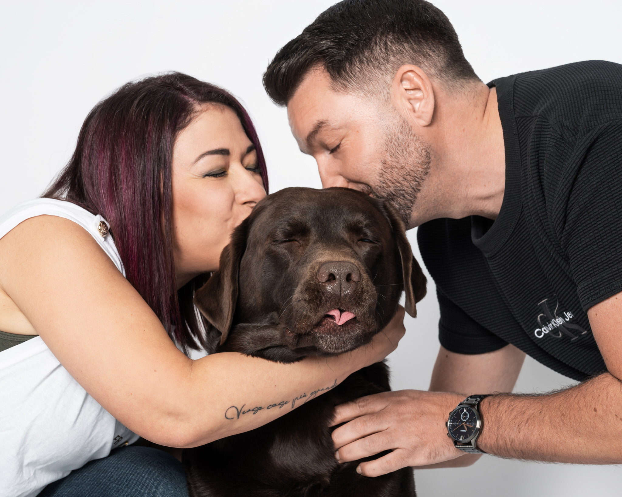 Paar küsst seinen Hund liebevoll im Studio